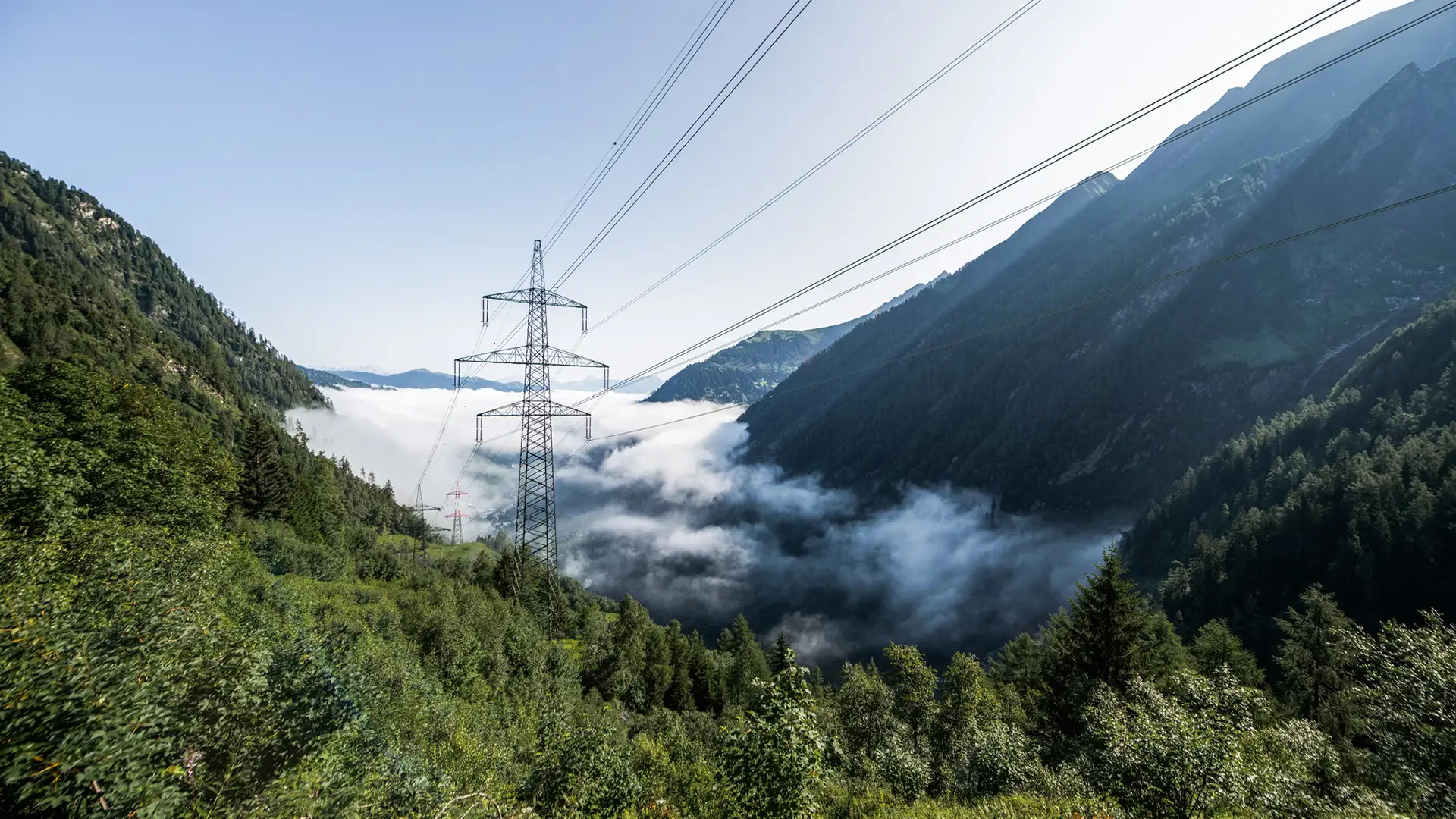 VERBUND Hochstromleitung zwischen saftig grünen Bergen.