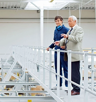 Zwei Personen stehen in einer Industrieanlage und besprechen sich.